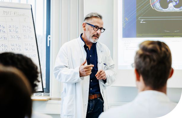 medical professional wearing a lab coat teaches classroom of PA students